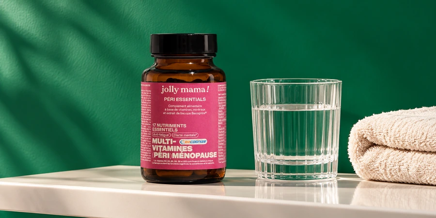 Pot ambré Péri essentials de Jolly Mama à étiquette rose posé près d’un verre d’eau et d’une serviette pliée