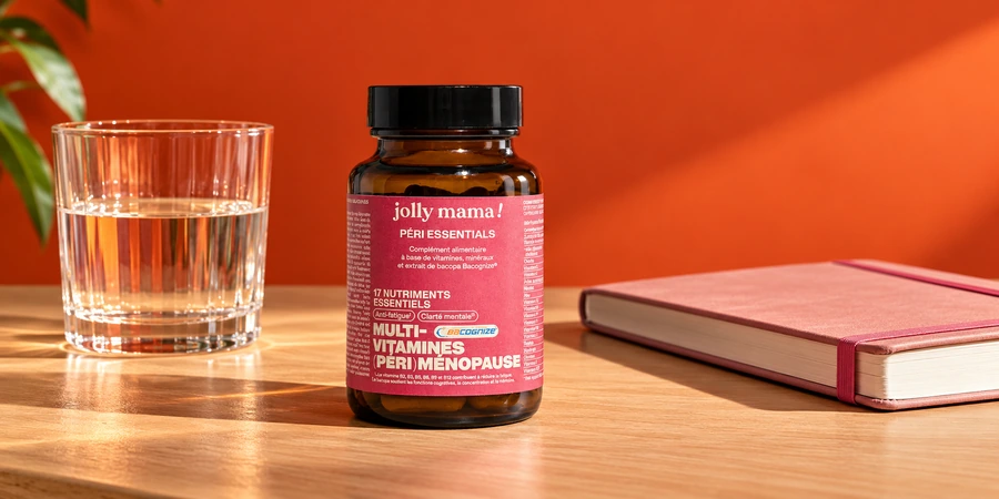 Pot ambré Péri essentials de Jolly Mama à étiquette rose posé sur un bureau à côté d’un verre d’eau et d’un carnet